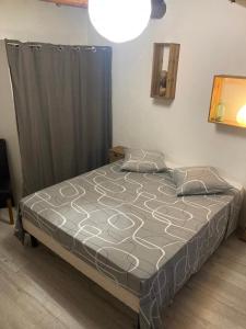 ein Schlafzimmer mit einem Bett mit einer grauen Bettdecke in der Unterkunft Lou camin dou cagnard in Méthamis