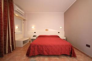 a bedroom with a bed with a red bedspread at Hotel Campanello in Castelnuovo del Garda
