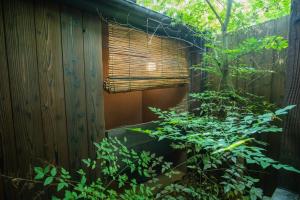 un edificio de madera con ventana y algunas plantas en 京·馨 en Kioto