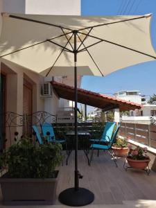 een parasol op een patio met stoelen en een tafel bij PERLA apartments in Paralia Dionysiou