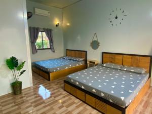 2 camas en una habitación con un reloj en la pared en Hotel Cù Lao 1, en Ấp Thanh Sơn (1)