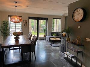 a living room with a table and a clock on the wall at Bosboerderij de Goudsberg in Lunteren