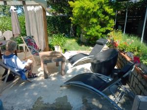 un hombre sentado en una silla en un patio en studio chez l'habitant, en Pierrelatte