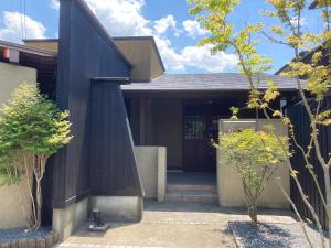 una casa con una fachada negra con una escalera que conduce a ella en YUFUIN YUKI-AN en Yufu