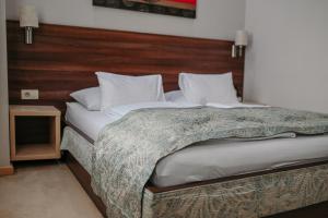 a bedroom with a large bed with a wooden headboard at Boutique Hotel Ukus in Tešanj