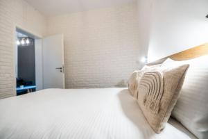 - une chambre avec un lit doté de draps et d'oreillers blancs dans l'établissement Guest Studio, à Braşov