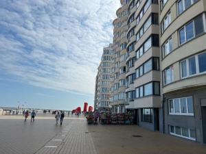 a building on the beach with people walking down a street at Luxe appartement met adembenemend uitzicht op zee in Ostend