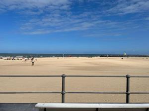 a bench in front of a beach with a fence at Luxe appartement met adembenemend uitzicht op zee in Ostend
