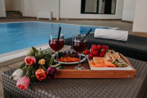 una bandeja de comida y copas de vino junto a una piscina en Boutique Hotel Ukus, en Tešanj