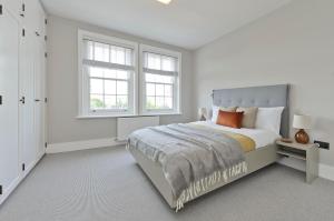 a white bedroom with a bed and two windows at Fabulous three bedroom flat near Marylebone by UnderTheDoormat in London