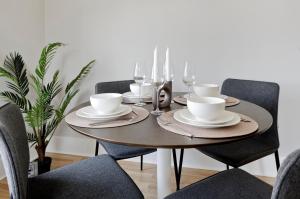 a dining room table with chairs and a wooden table with glasses at Fabulous three bedroom flat near Marylebone by UnderTheDoormat in London