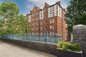 een groot bakstenen gebouw met een hek ervoor bij Fabulous three bedroom flat near Marylebone by UnderTheDoormat in Londen