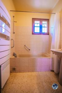 baño con bañera, lavabo y ventana en Petit Mas au calme proche centre, en Bagnols-sur-Cèze