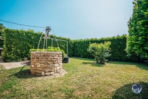 un jardín con una pared de piedra y una red en Petit Mas au calme proche centre, en Bagnols-sur-Cèze