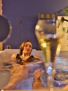 Eine Frau sitzt in einer Badewanne in der Unterkunft La Parenthèse Envoutée in Amiens