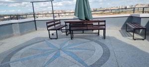 a patio with two benches and an umbrella on a roof at Studio 47 Ensuite Apartment in Donholm Phase 5G Estate, Nairobi in Nairobi