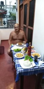 un hombre sentado en una mesa con platos de comida en Pearl Resort Mirissa, en Mirissa