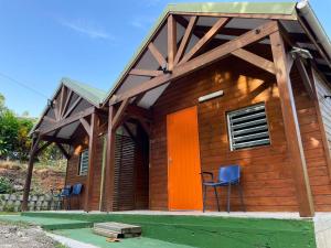 a log cabin with two chairs and a roof at Bungalow charmant à Petit-Bourg avec jardin privé in Petit-Bourg