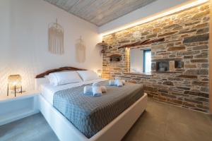 a bedroom with a bed and a stone wall at Falakis Apartments in Kithnos