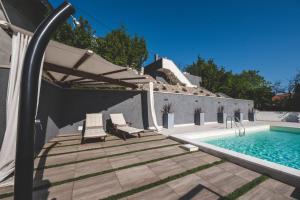 a swimming pool with two chairs and an umbrella at Beachfront Villa Grace with heated rooftop pool in Jadranovo