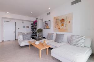 Neve Tzedek Apartment-Hosted by Sweetstay في تل أبيب: غرفة معيشة مع كنبتين بيضاء وطاولة