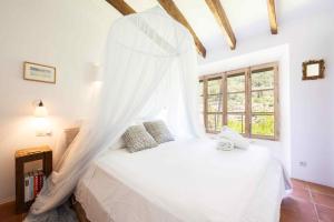 a bedroom with a white bed with a mosquito net at CA'N LA in Deia