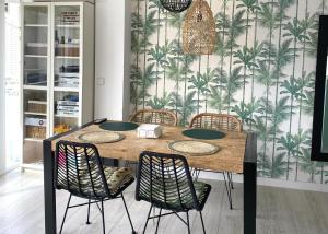 a dining room table with chairs and a tropical wallpaper at Cozy apartment Benidorm Poniente 5 min from the beach in Benidorm