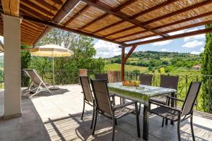 un patio con mesa y sillas bajo una pérgola de madera en TORREVISTA - Opened 2022, en Montaione