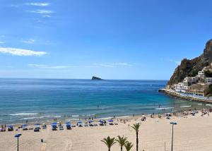 a beach with umbrellas and people in the ocean at Cozy apartment Benidorm Poniente 5 min from the beach in Benidorm