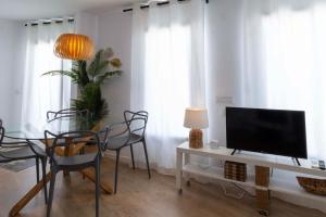 ein Wohnzimmer mit einem TV und einem Tisch mit Stühlen in der Unterkunft Apartament Les Cases in Les Cases d'Alcanar
