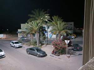 un grupo de coches estacionados en un estacionamiento con palmeras en Appartement Fethia en Houmt El Souk