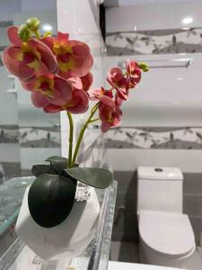 a vase with pink flowers on a counter in a bathroom at 3 Bed DD Luxury Apt SMCHS in Karachi