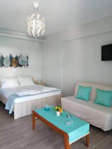 um quarto com uma cama, um sofá e uma mesa em PERLA apartments em Paralia Dionysiou