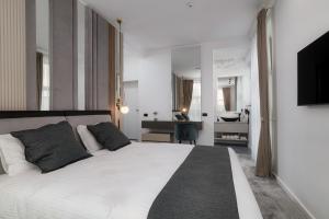 a bedroom with a large white bed and a desk at Peninsula Luxury & Spa in Năvodari