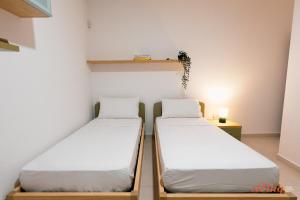 2 camas en una habitación pequeña con estantería en A pretty holiday home in Malta’s fishing village, en Marsaxlokk