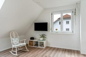 a white living room with a chair and a window at Haus 23 in Ettenheim