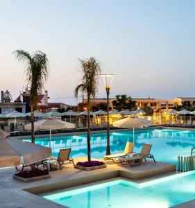 a large swimming pool with chairs and umbrellas at Porto Platanias Village Resort in Plataniás