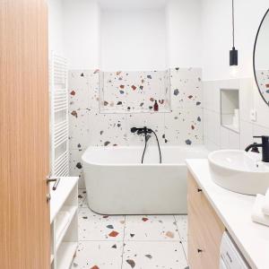 Baño blanco con bañera y lavamanos en Aumetz square apartment, en Idrija
