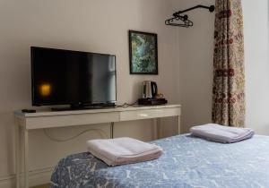 a bedroom with a tv and a bed with two towels at Manorbier House - Caldey Island Room in Tenby