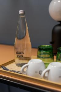 a bottle of water and cups on a table at Stay Swanky Bed & Breakfast in Zagreb