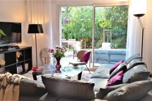 a living room with a couch and a glass table at Villa dans un puits de verdure avec piscine résidentielle in Valbonne