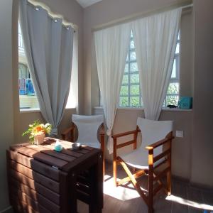 een woonkamer met stoelen en een tafel en ramen bij PERLA apartments in Paralia Dionysiou