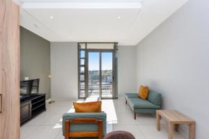 Johannesburg的住宿－The Median Rosebank Luxury Apartment - Building with Generator，客厅配有两把椅子和电视