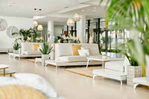 a lobby with white couches and tables and plants at Iberostar Waves Cristina in Playa de Palma