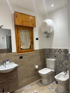 ein Badezimmer mit einem WC, einem Waschbecken und einem Spiegel in der Unterkunft An Eye on Taormina in Letojanni