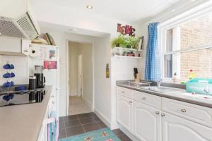 a kitchen with white cabinets and a sink and a window at Charming 3BD Flat - 5 Minutes to Victoria Park in London