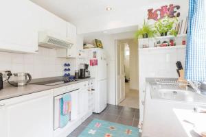 a kitchen with white cabinets and a sink at Charming 3BD Flat - 5 Minutes to Victoria Park in London