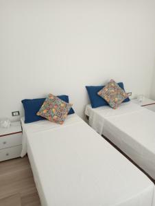 two beds in a room with white walls and blue pillows at Butterfly Apartments in Palermo
