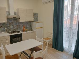 una pequeña cocina con una mesa blanca, una mesa y una ventana en Butterfly Apartments, en Palermo