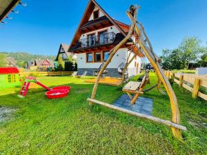 a house with a playground with a swing at Gąsienicowy Widok in Poronin